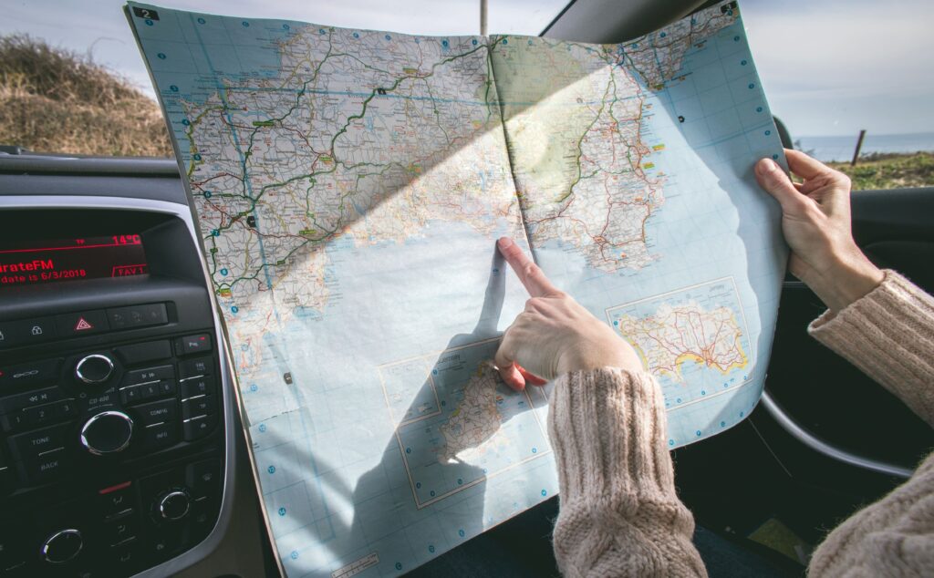 Person zeigt auf eine Landkarte im Auto