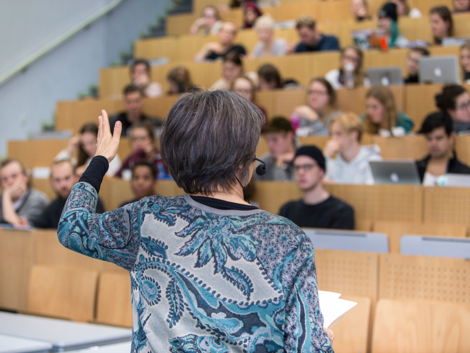 Eine Lehrende spricht vor Zuhörern im vollen Hörsaal.